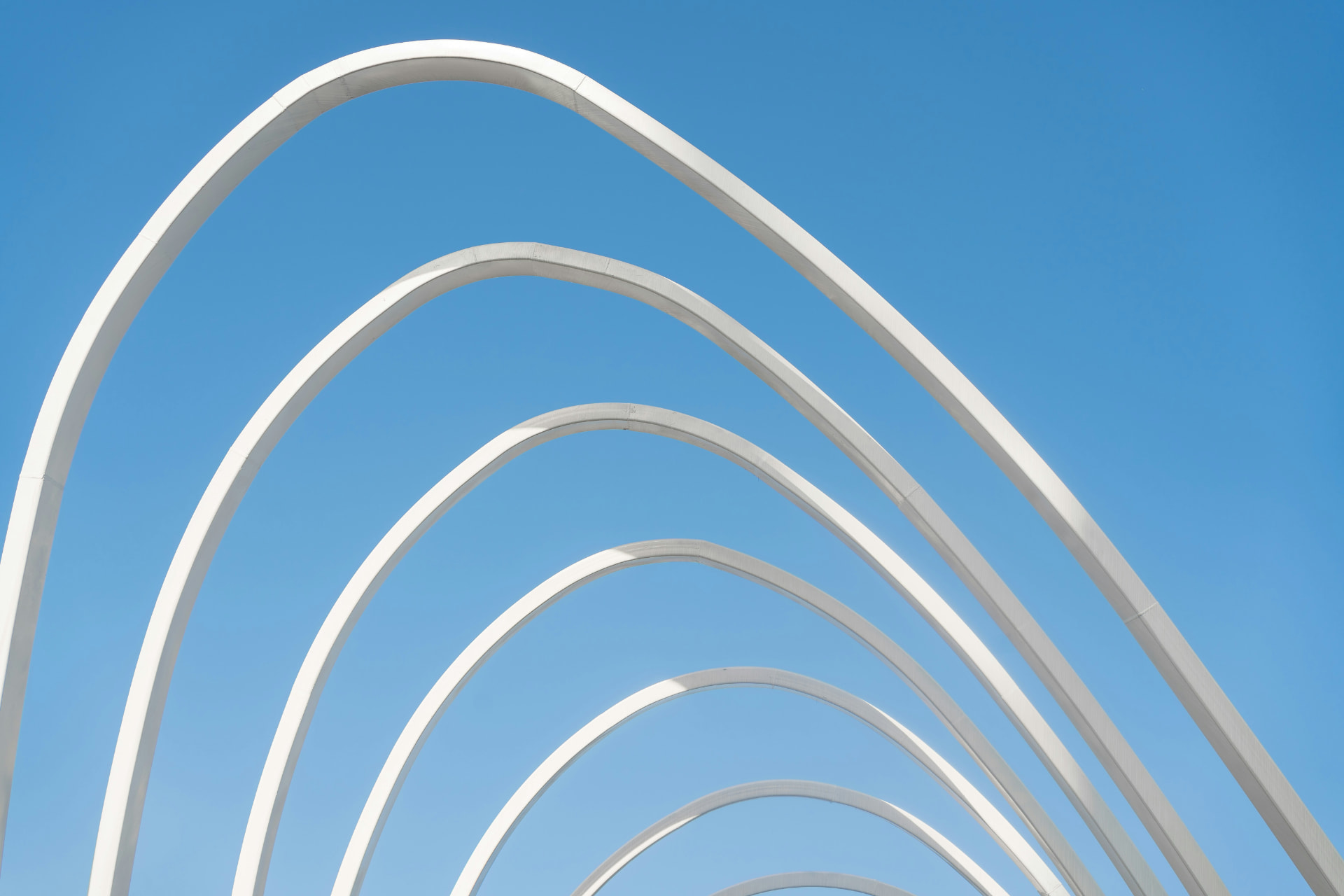 White structural arches against a clear sky